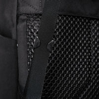 Close-up of a black backpack strap and textured back panel