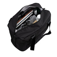 A black nylon duffel bag shown open, revealing its interior storage capacity filled with travel items such as a laptop, shoes, and toiletry bottles, on a solid white background.