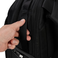 Hand holding side handle of black backpack