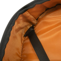 close up of black backpack with orange lining and strap