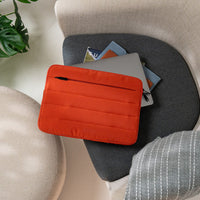 Red laptop sleeve on a gray chair with a plant in the background