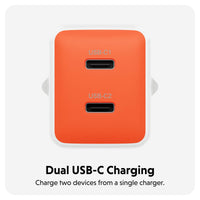 An orange dual USB-C charging adapter with two USB-C ports, shown on a light gray background with text below reading 'Dual USB-C Charging' and 'Charge two devices from a single charger.'.