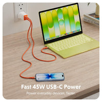 An orange USB-C charging cable shown plugged into a wall outlet and connected to a laptop and smartphone on a wooden desk, with text reading 'Fast 45W USB-C Power' at the bottom.
