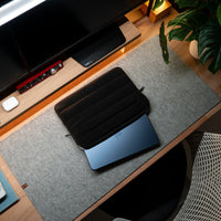Black laptop case on a desk with a computer setup in the background