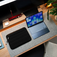 Laptop on a desk with a black sleeve next to it