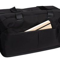 A black duffel bag with a front utility pocket holding a beige notebook, shown on a plain white background.