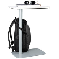 Small table with a backpack securely strapped to table and sunglasses on a white background