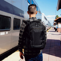 Man with a black Targus backpack standing on a train platform