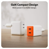 Two compact GaN chargers on a wooden surface against a soft light gray background. One charger is plain white, and the other is white with a bright orange front panel.