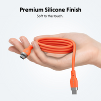 An orange USB-C cable with a coiled loop held in a hand, showing both USB-C connectors, with text at the top reading 'Premium Silicone Finish' and 'Soft to the touch.'.